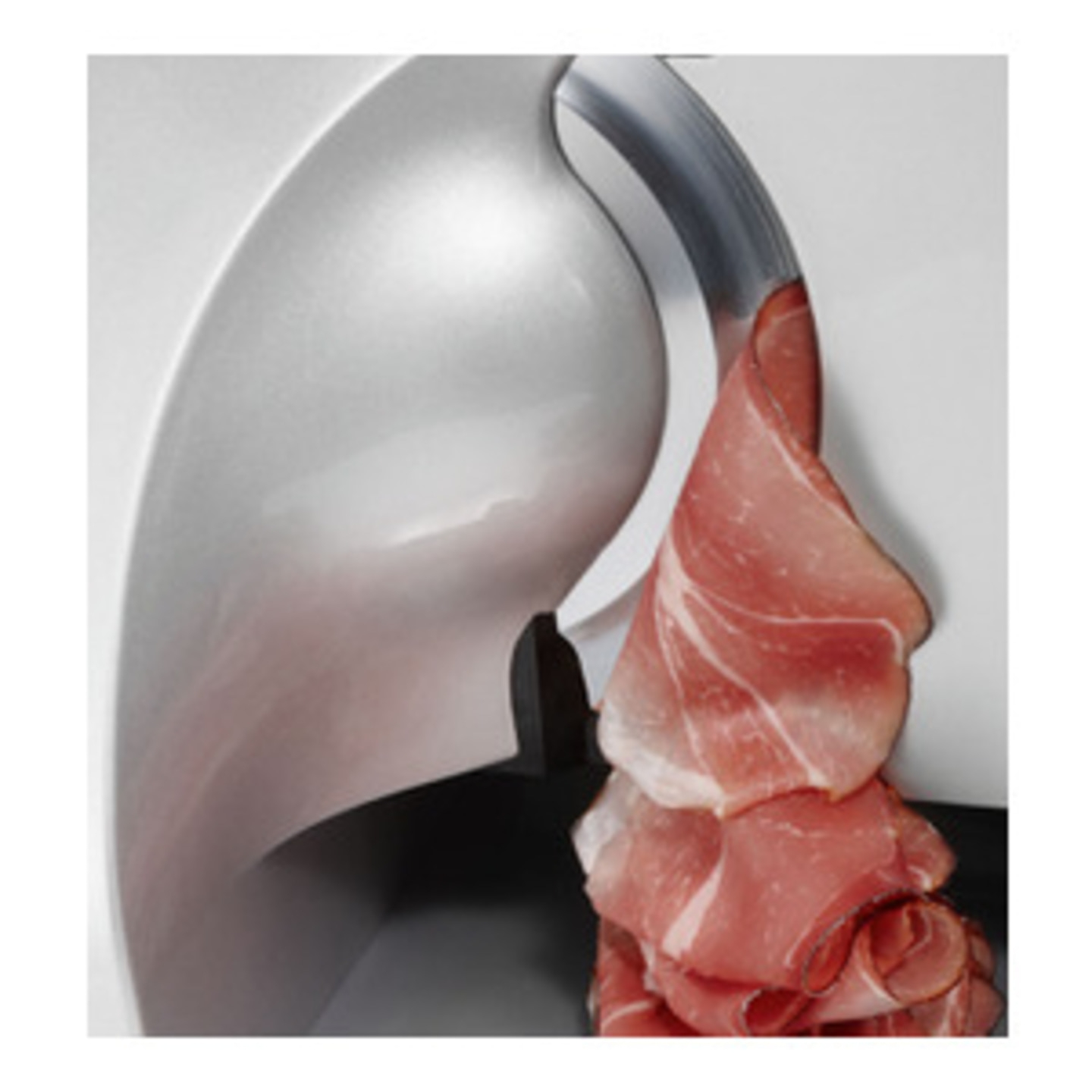 Close-up of a meat slicer cutting thin slices of meat, likely prosciutto.