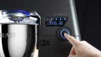 Robot de cuisine avec écran numérique et molette, doigt touchant la molette