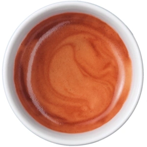 Nahaufnahme einer Tasse Espresso mit cremiger Oberfläche und Wirbeln.