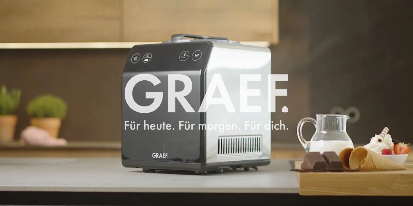 GRAEF Eiscreme-Maschine mit Eisbecher, Schokolade und Milchkanne auf einer Theke.