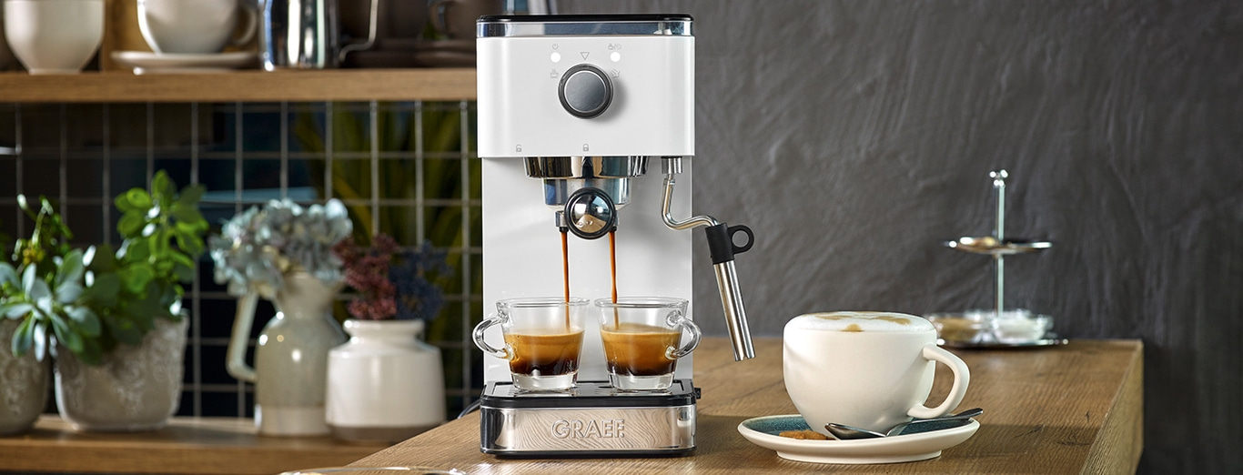 Machine à expresso avec deux tasses, cappuccino et décorations sur une table en bois
