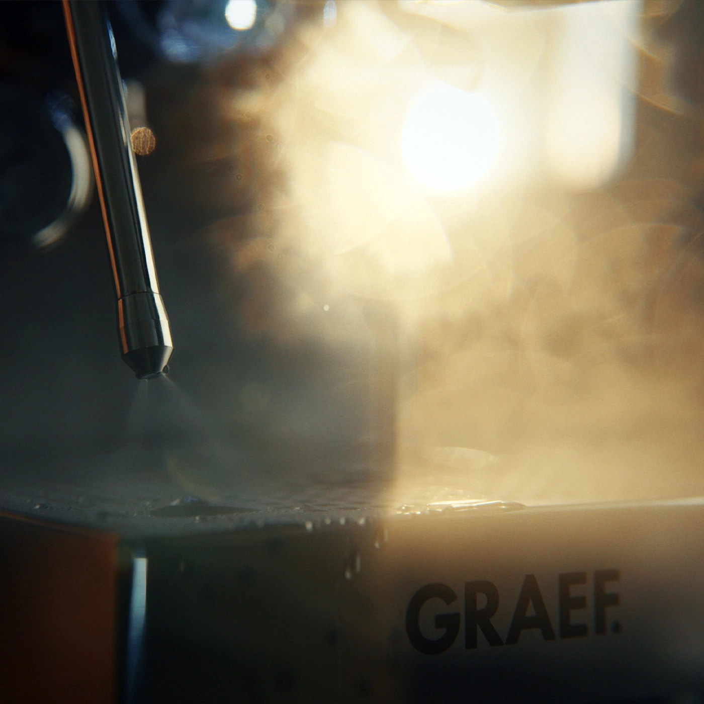 A steam jet hits a water surface with the GRAEF logo.