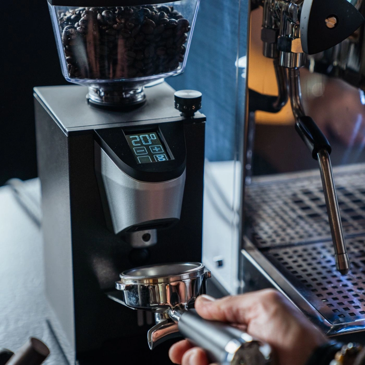 Kaffeemühle mit Bohnen und Siebträger in der Hand, nahaufnahme
