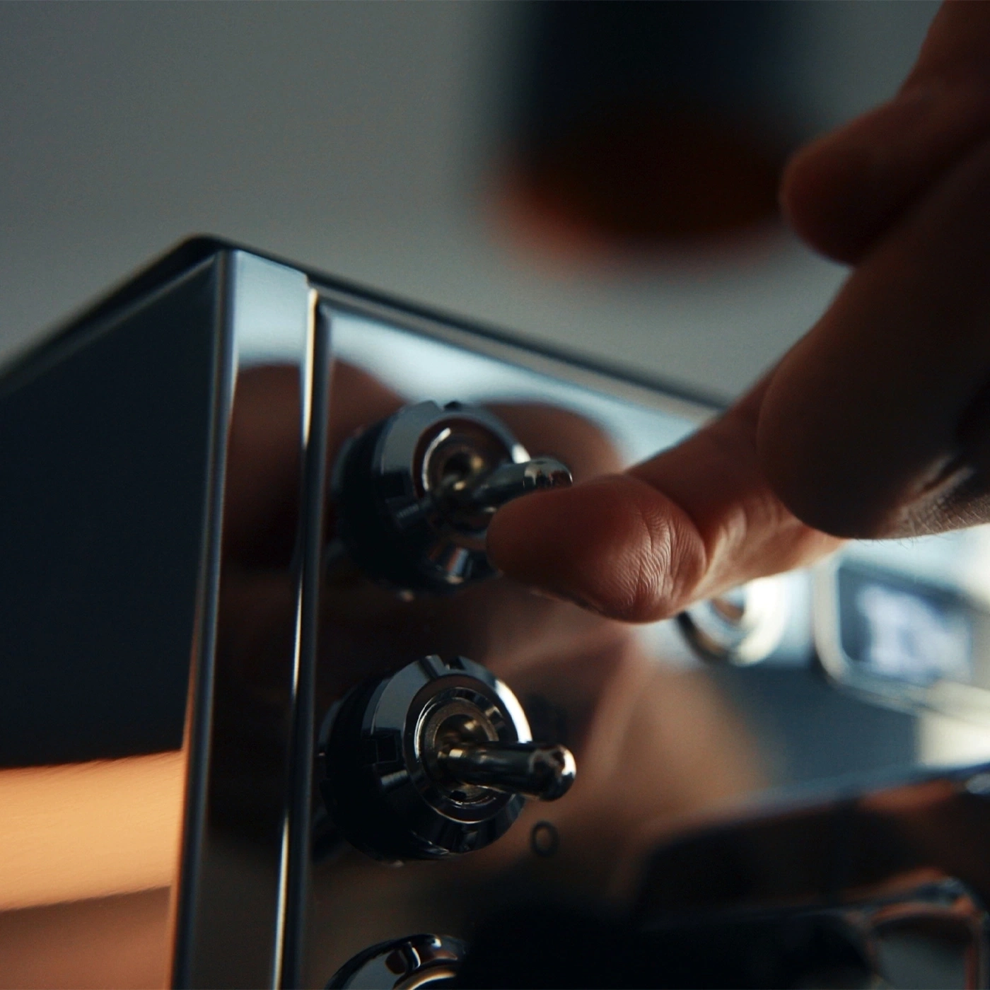 A finger flips a toggle switch on a shiny appliance.