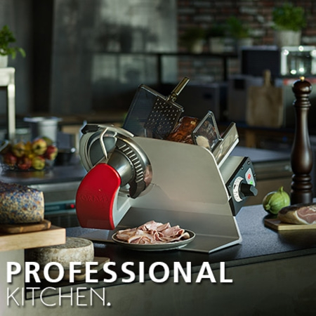 Professionelle Küche mit Fleischschneidemaschine und Essen auf dem Tisch.