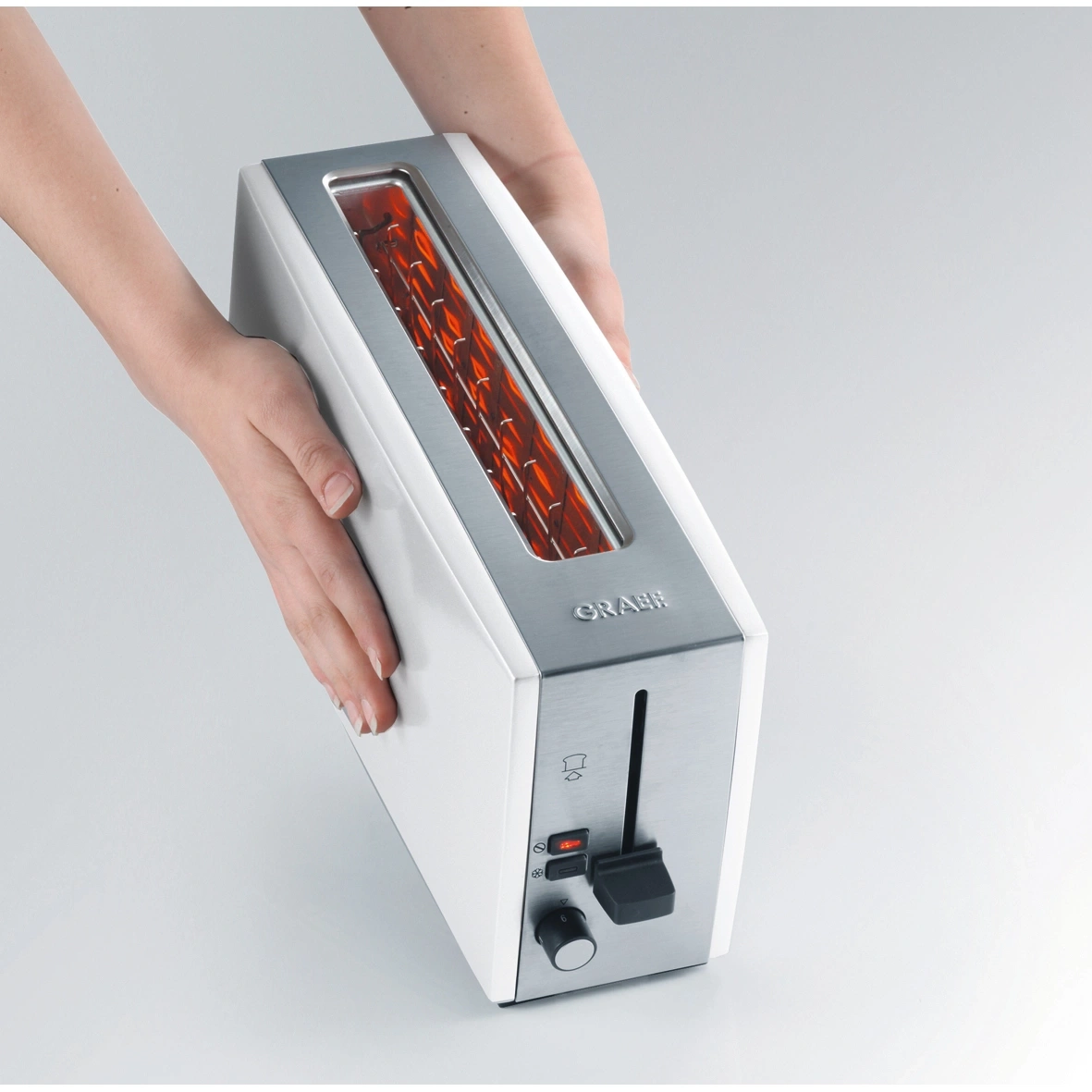 Ein weißer Toaster mit silbernen Akzenten wird von Händen gehalten.