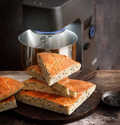 Bread on wooden board with a kitchen machine in the background