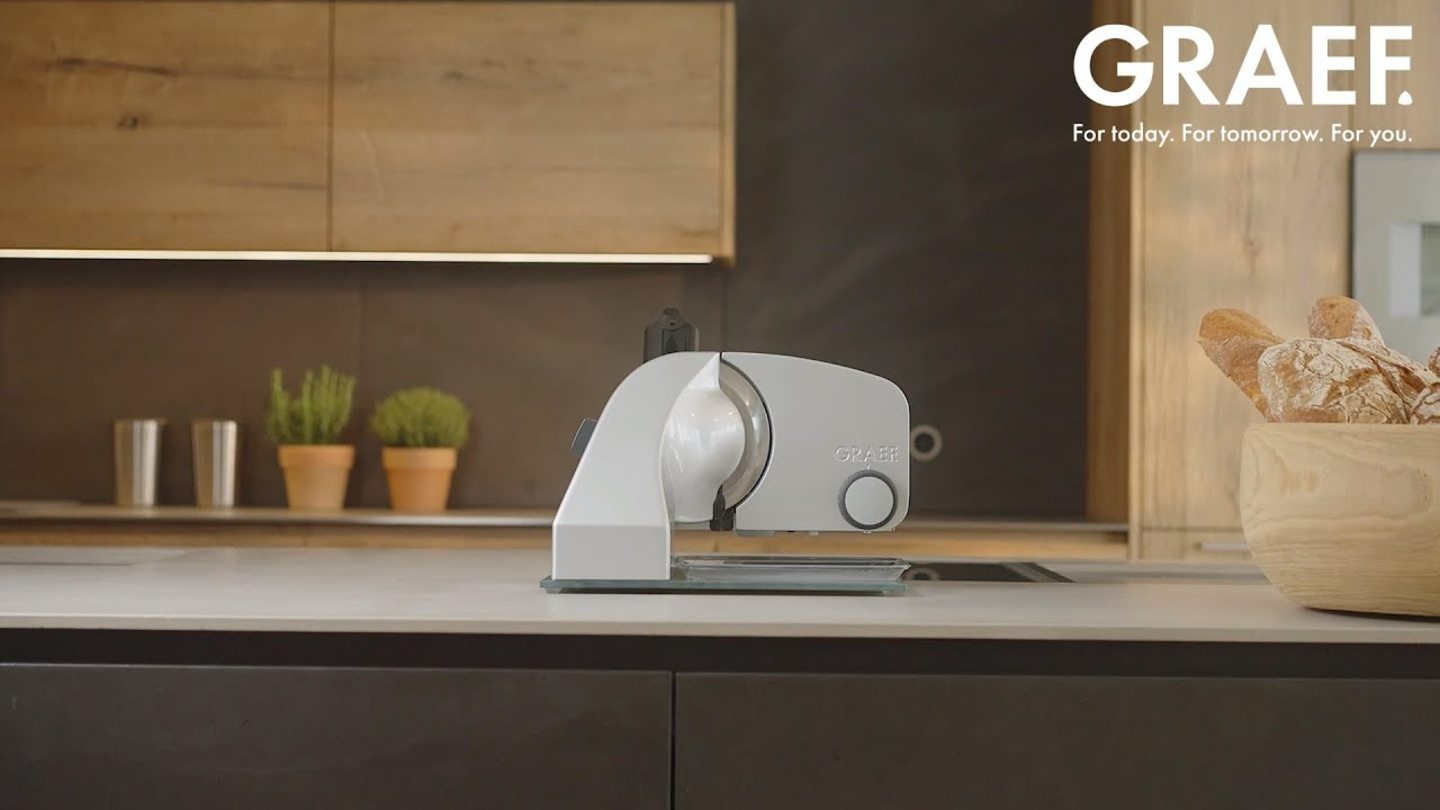 Graef slicer on kitchen counter with bread and plants in the background