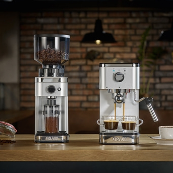 Kaffeemaschine und Kaffeemühle auf einem Holztisch. Espresso wird zubereitet.