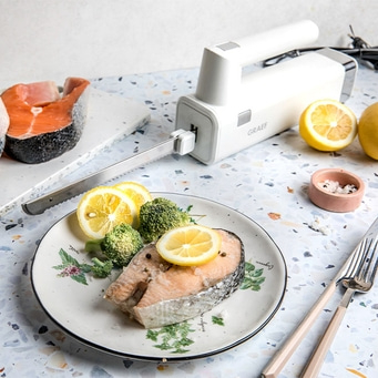 Lachsfilet mit Zitrone und Brokkoli, serviert mit Messer und Gabel.