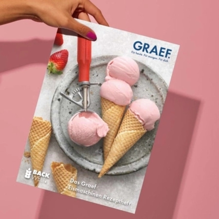 Hand holding magazine with ice cream cones and strawberries on pink background