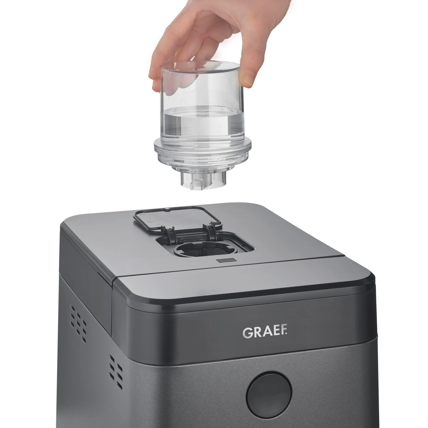 Hand hält einen Wasserfilter über einem grauen Gerät mit der Aufschrift GRAEF.