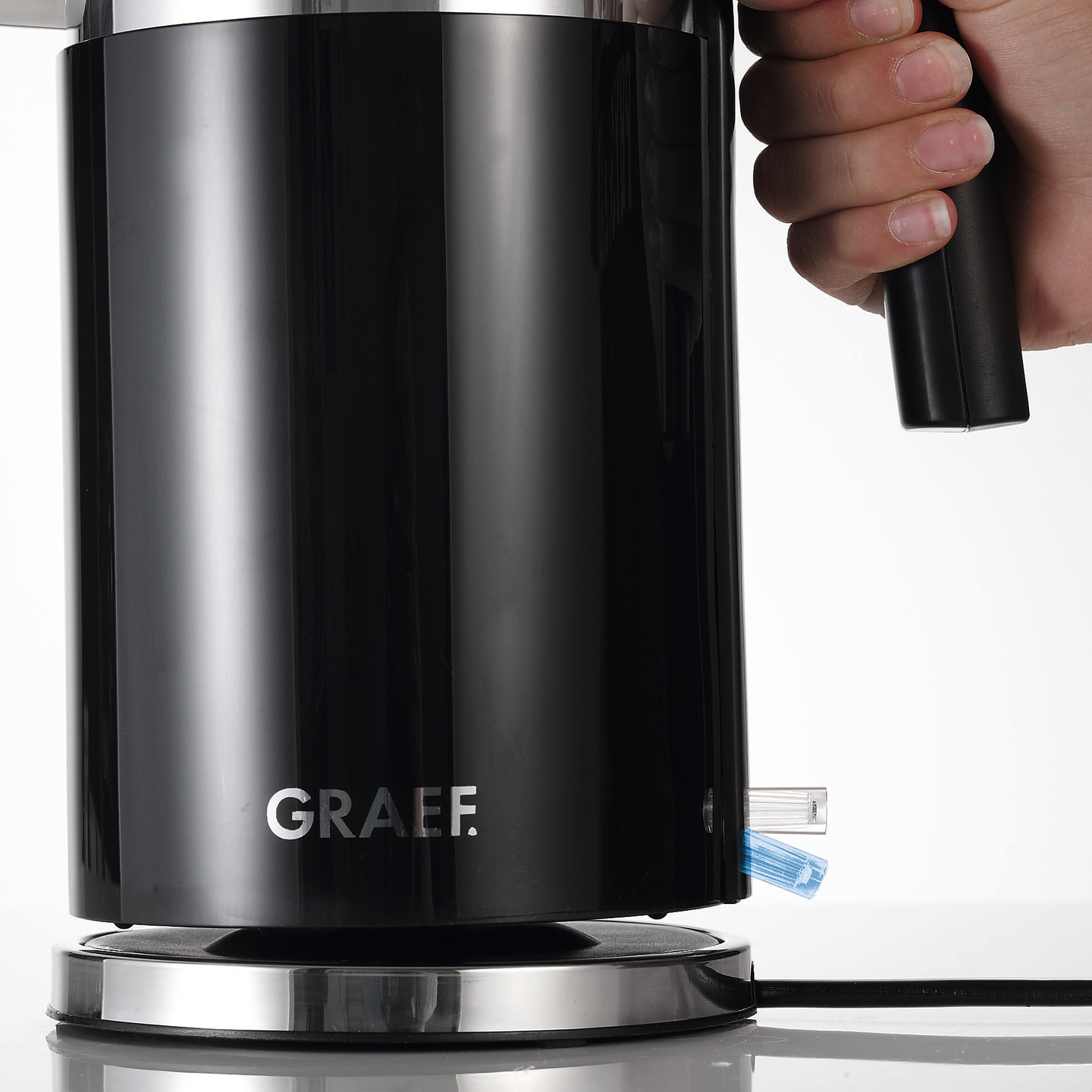Schwarzer Wasserkocher mit Hand und GRAEF-Logo, Detailaufnahme, glänzend.