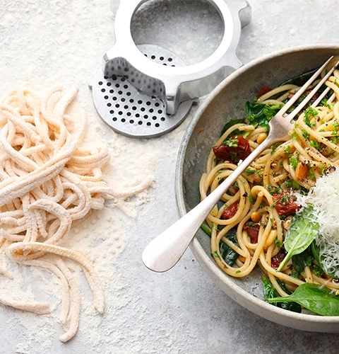 Pasta with tomatoes and spinach in a bowl with a fork