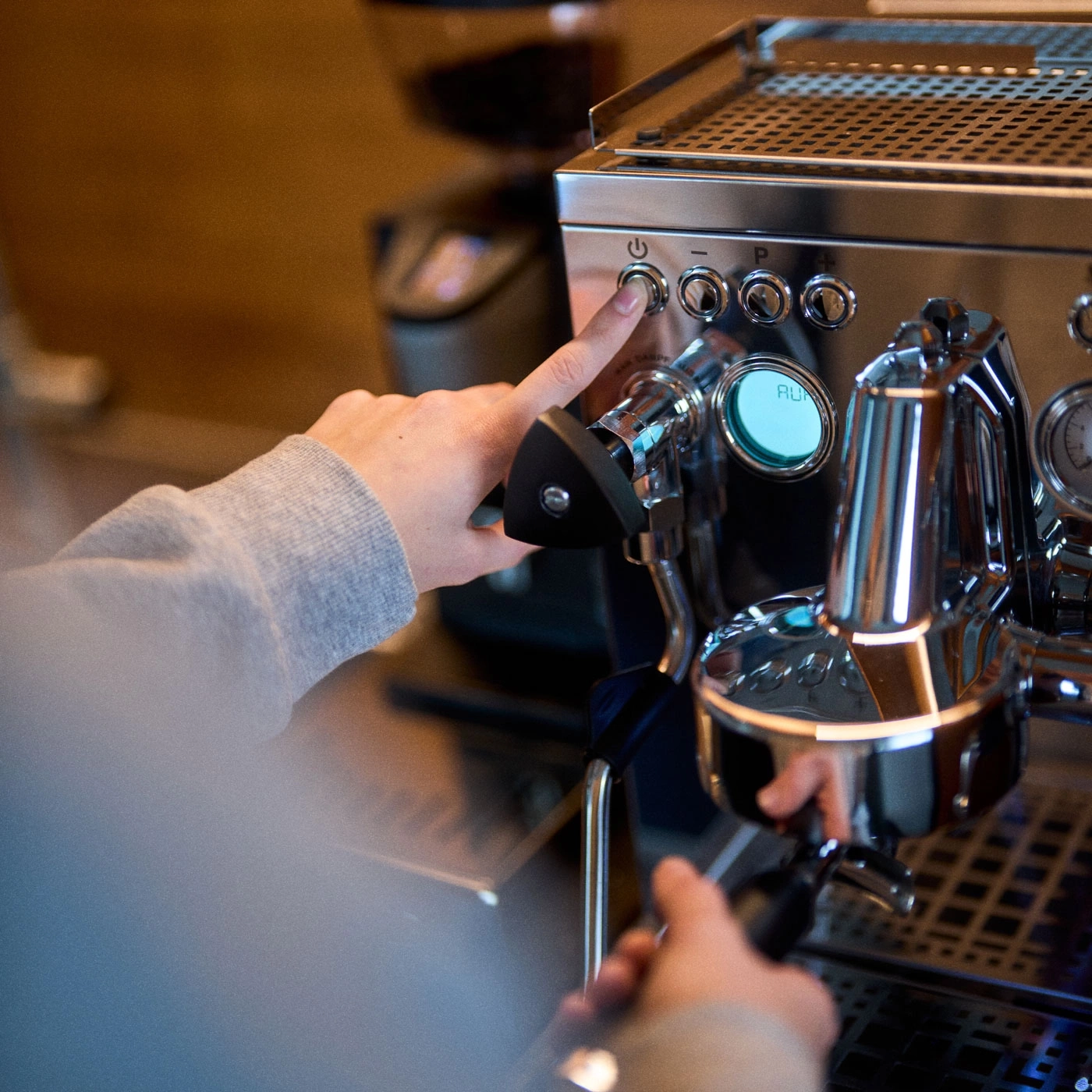 Person drückt Knopf an einer Espressomaschine, um sie einzuschalten.
