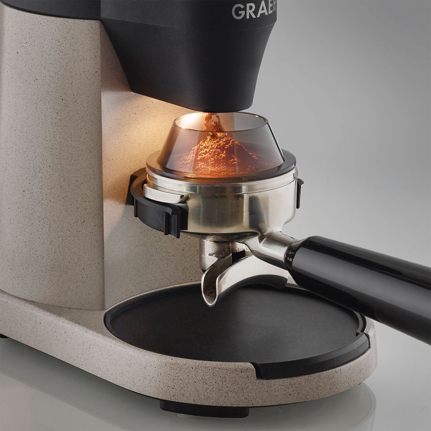 Kaffeemühle mit Kaffeepulver im Siebträger, Nahaufnahme, beleuchtet, grau