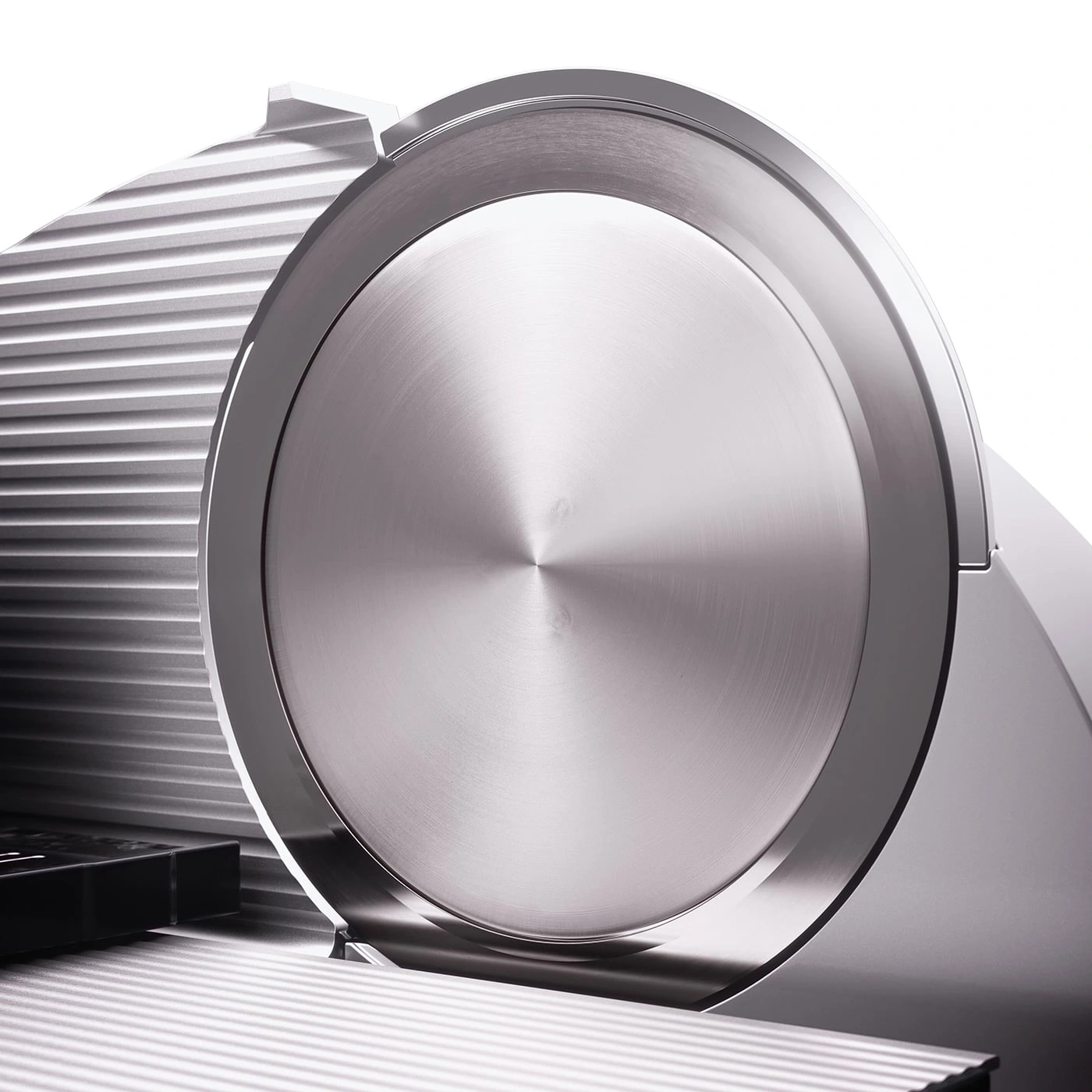 Close-up of a silver meat slicer with circular blade and ridged surface