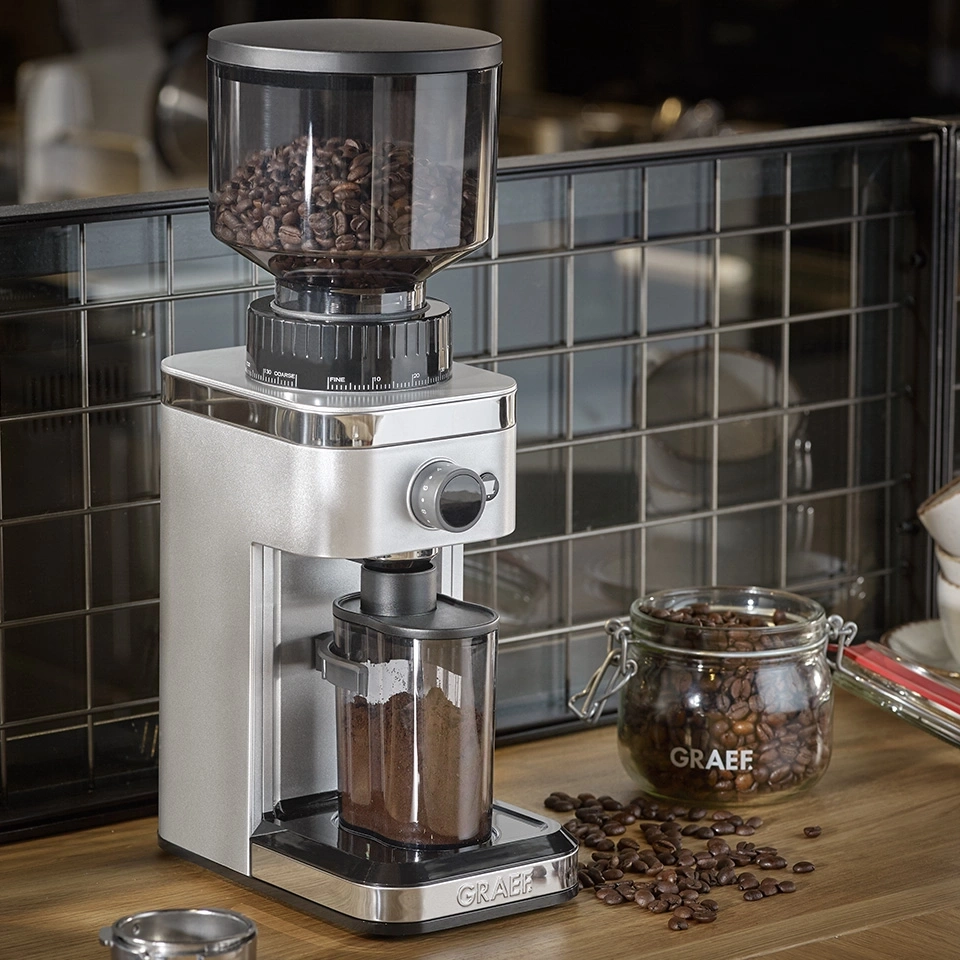 Moulin à café avec grains et bocal en verre sur surface en bois
