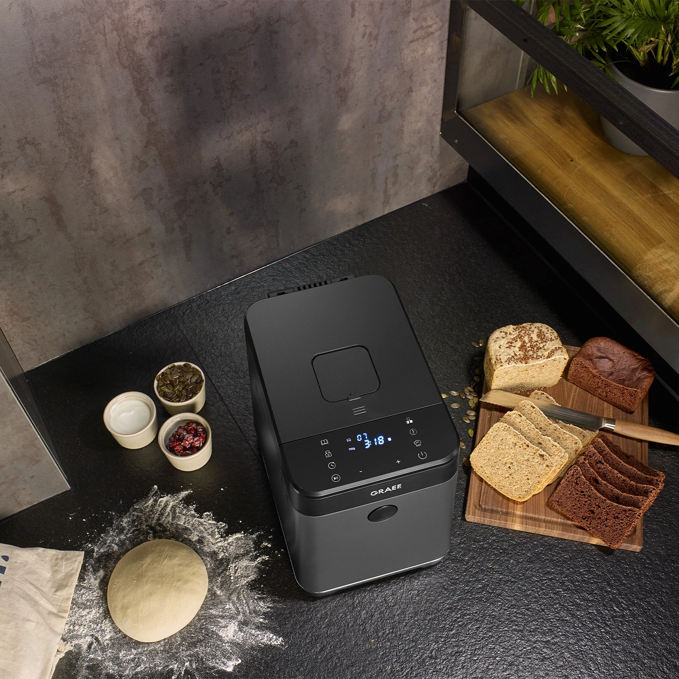 Machine à pain avec pain, ingrédients et pâte sur une table noire