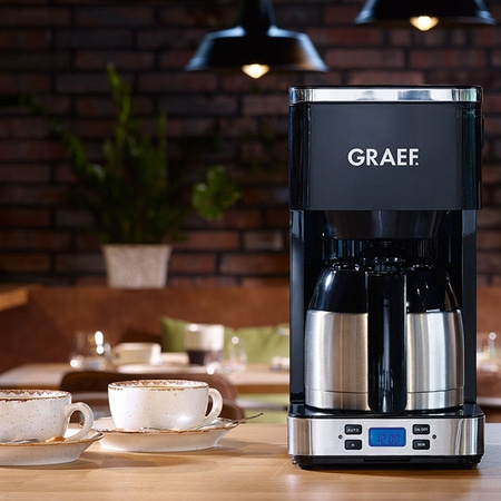 Kaffeemaschine mit Tassen auf einem Holztisch, GRAEF-Logo, Innenraum