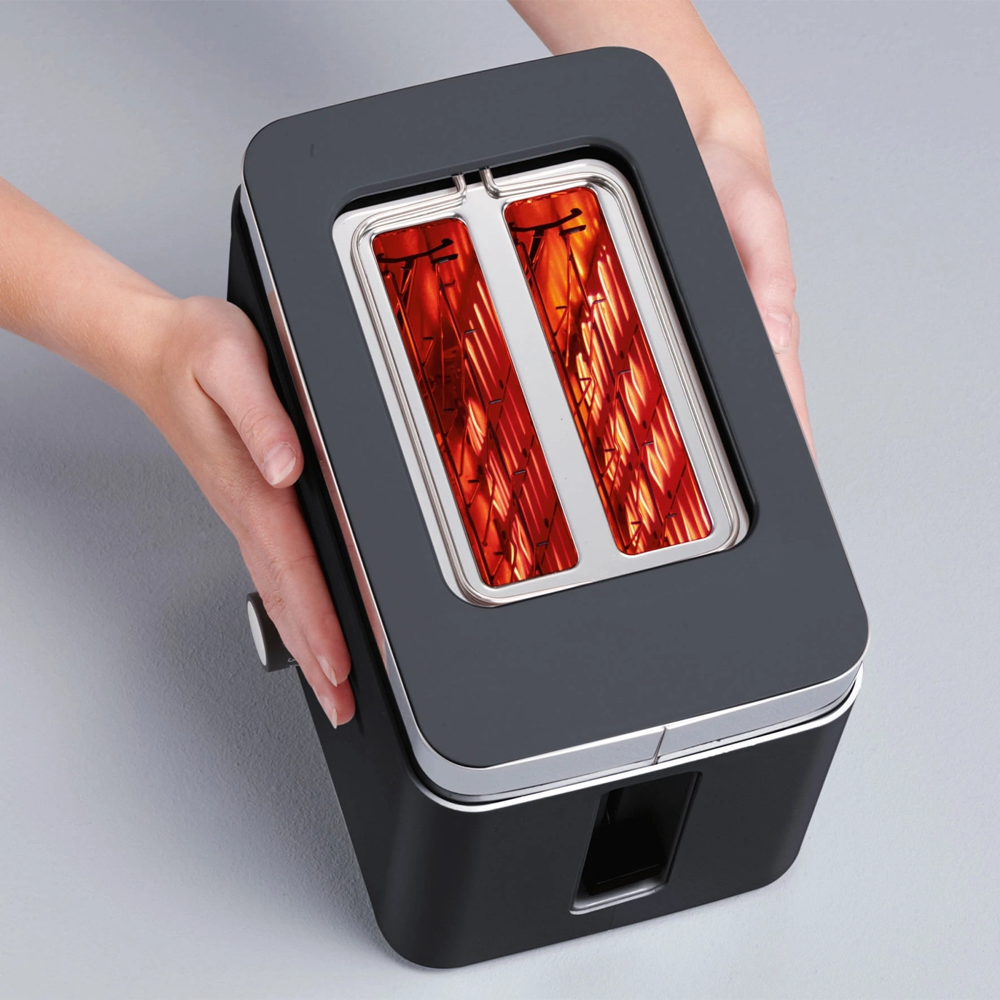Toaster held in hands, with glowing heating elements, ready to toast bread.