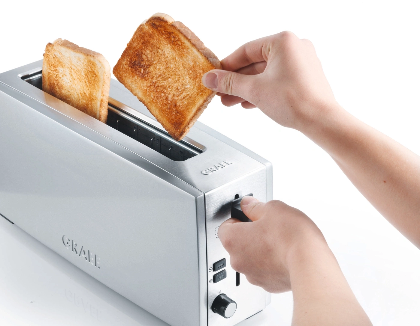 Person entnimmt Toast aus Toaster. Silberner Toaster mit Toastbrot.